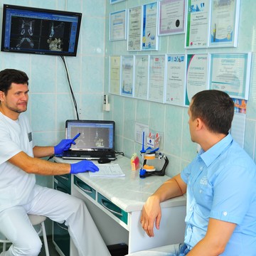 Врач стоматолог- ортопед Овчинников Денис Владимирович проводит консультацию пациента на основе компьютерной 3D томографии